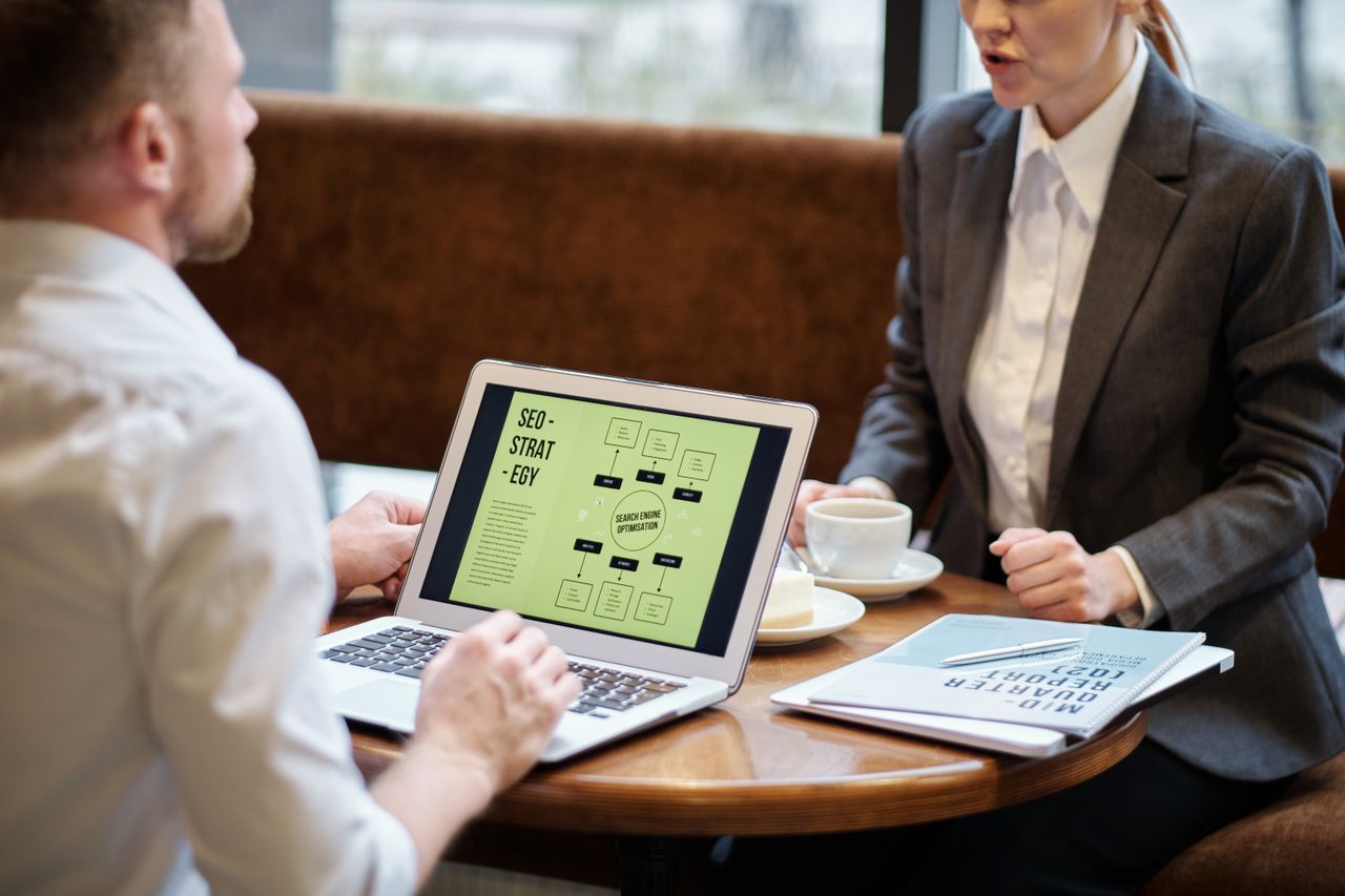 home-hero-bg A man and woman engaged in a business meeting discussing SEO strategy in a cozy cafe setting.